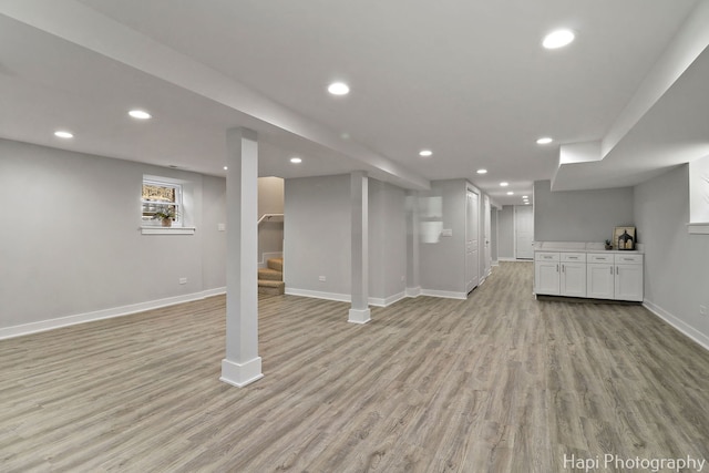 below grade area with light wood-style flooring, baseboards, recessed lighting, and stairs