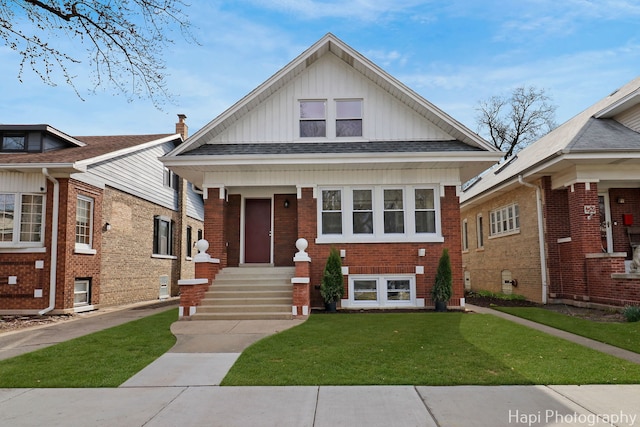 bungalow featuring board and batten siding, brick siding, a shingled roof, and a front lawn