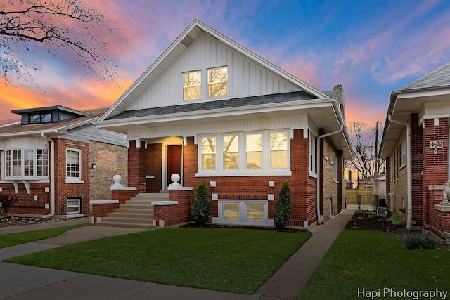 bungalow-style home featuring board and batten siding, a yard, and brick siding