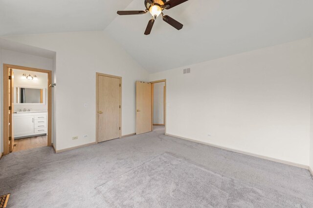 unfurnished bedroom featuring baseboards, visible vents, lofted ceiling, and light colored carpet