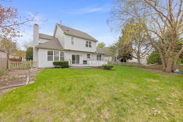 back of house with a lawn, a fenced backyard, a wooden deck, and a chimney
