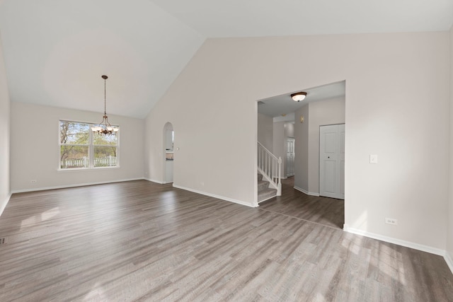 interior space with arched walkways, wood finished floors, a chandelier, and stairway
