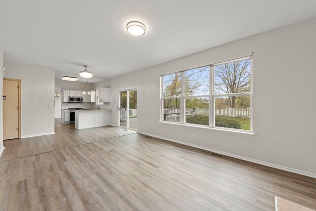 unfurnished living room with baseboards, visible vents, and light wood-type flooring