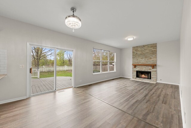 unfurnished living room with baseboards, an inviting chandelier, and wood finished floors