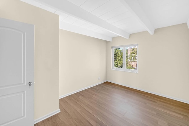 unfurnished room with beam ceiling, baseboards, and wood finished floors