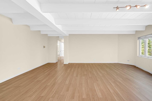 unfurnished room featuring baseboards, light wood-style floors, and beam ceiling