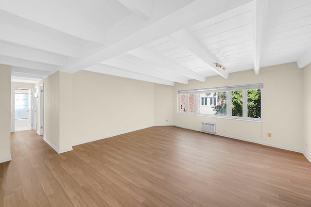 empty room featuring light wood-style flooring, baseboards, a wall mounted air conditioner, and beamed ceiling