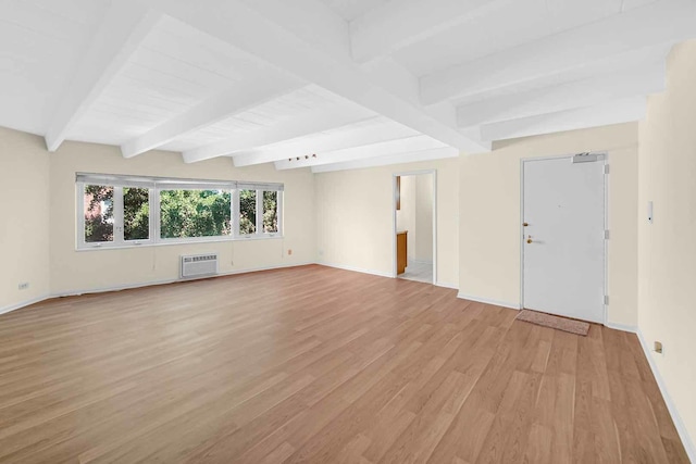 unfurnished room with baseboards, a wall unit AC, light wood-style floors, and beam ceiling
