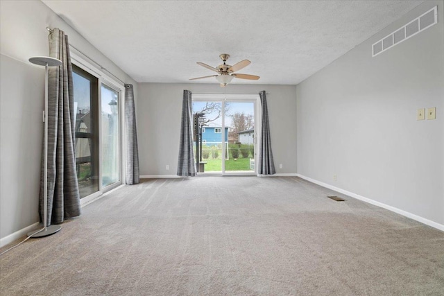carpeted spare room featuring visible vents, baseboards, and ceiling fan