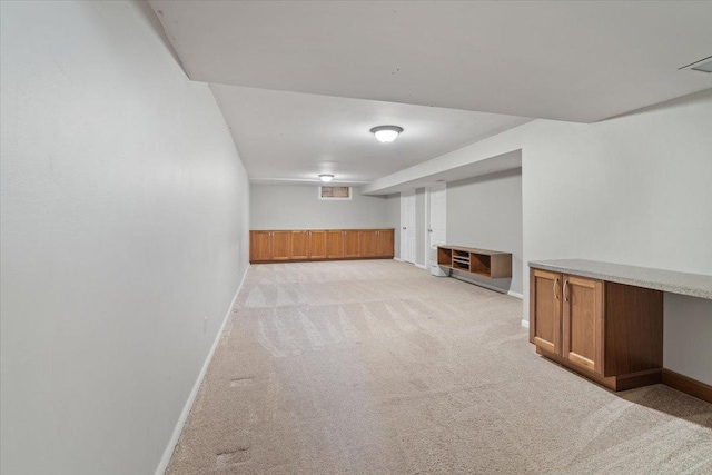 finished basement featuring baseboards and light colored carpet
