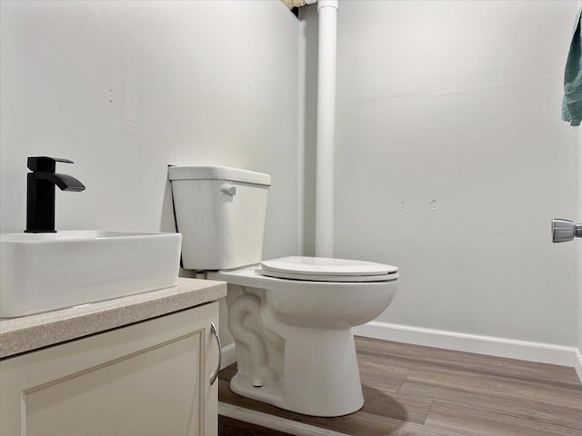 bathroom featuring toilet, vanity, wood finished floors, and baseboards
