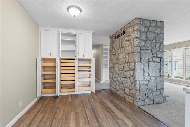 interior space with visible vents, a textured ceiling, baseboards, and dark wood finished floors