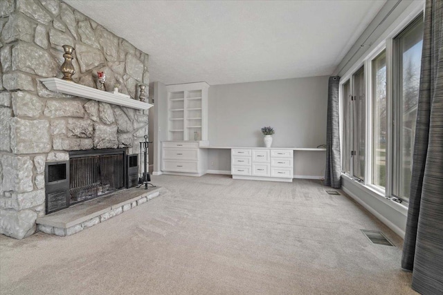 unfurnished living room featuring visible vents, baseboards, a stone fireplace, a textured ceiling, and carpet flooring