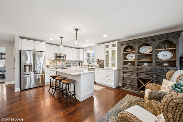 kitchen with white cabinetry, a center island, appliances with stainless steel finishes, a breakfast bar area, and dark wood-style floors