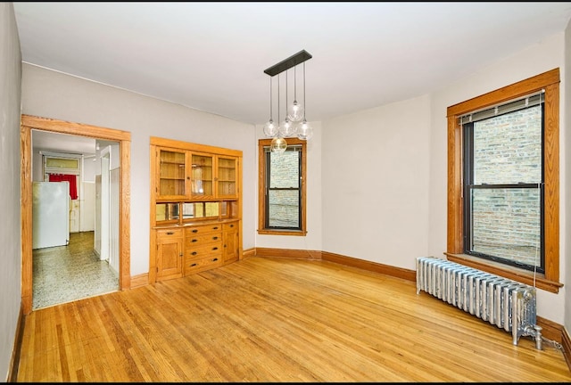 empty room featuring baseboards, wood finished floors, and radiator