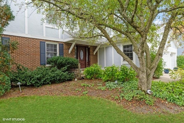 view of front of property featuring stucco siding, brick siding, and concrete driveway