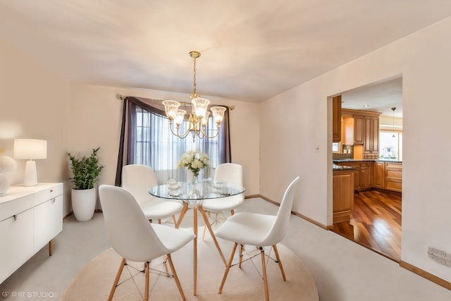 dining space featuring an inviting chandelier, light wood-style flooring, baseboards, and a wealth of natural light