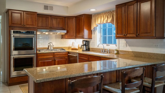 1336 Christina Ln, Northbrook, IL 60062 - kitchen with light stone counters, under cabinet range hood, visible vents, stainless steel appliances, and a sink