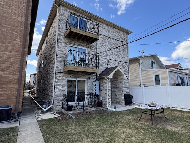 2915 N 74th Ave Unit 2, Elmwood Park, IL 60707 - rear view of house featuring a balcony, brick siding, fence, and a lawn