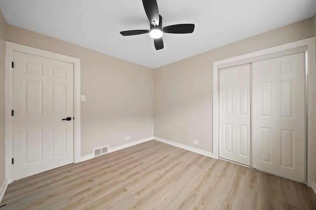 unfurnished bedroom featuring light wood-style floors, a closet, a ceiling fan, visible vents, and baseboards