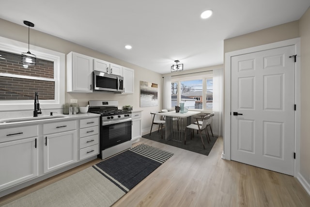 kitchen featuring light wood-style floors, white cabinets, light countertops, a sink, and stainless steel appliances