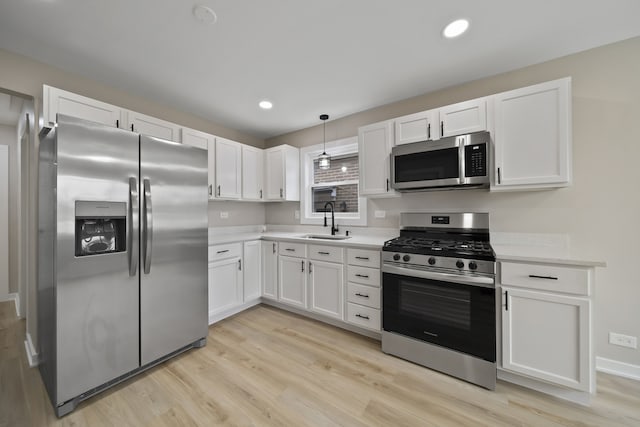 kitchen with light wood-type flooring, light countertops, white cabinetry, stainless steel appliances, and a sink