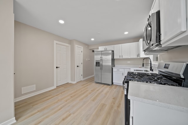 kitchen featuring recessed lighting, visible vents, stainless steel appliances, light wood finished floors, and a sink