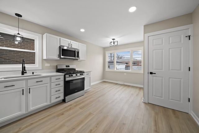 kitchen featuring stainless steel appliances, light wood finished floors, light countertops, and a sink