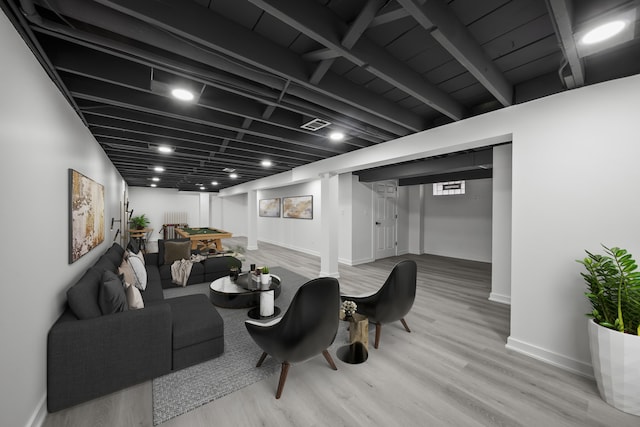 living room with visible vents, baseboards, radiator, and wood finished floors