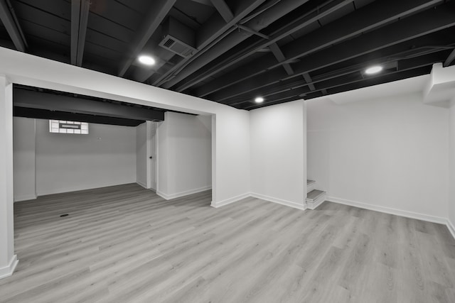 basement with visible vents, baseboards, and wood finished floors