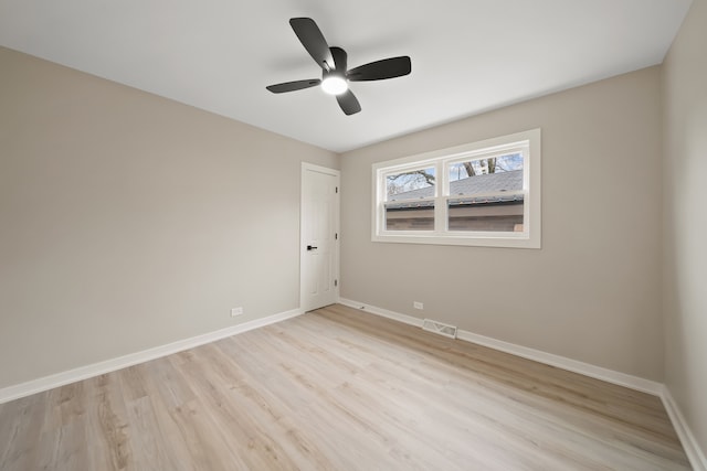 spare room featuring light wood finished floors, visible vents, baseboards, and a ceiling fan