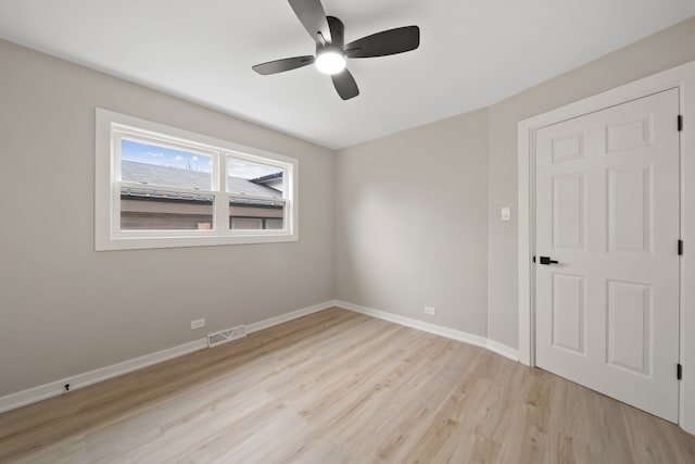 empty room with visible vents, baseboards, a ceiling fan, and light wood finished floors