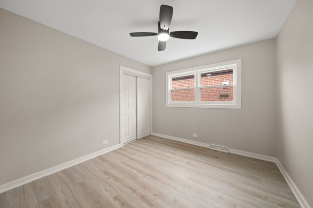 unfurnished bedroom featuring ceiling fan, light wood-type flooring, a closet, visible vents, and baseboards