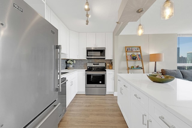 kitchen featuring stainless steel appliances, backsplash, light wood finished floors, white cabinets, and light stone counters