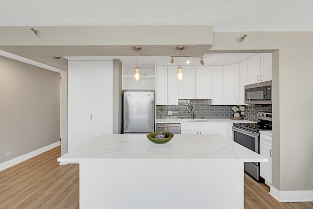 kitchen featuring stainless steel appliances, a sink, light wood-style flooring, tasteful backsplash, and baseboards