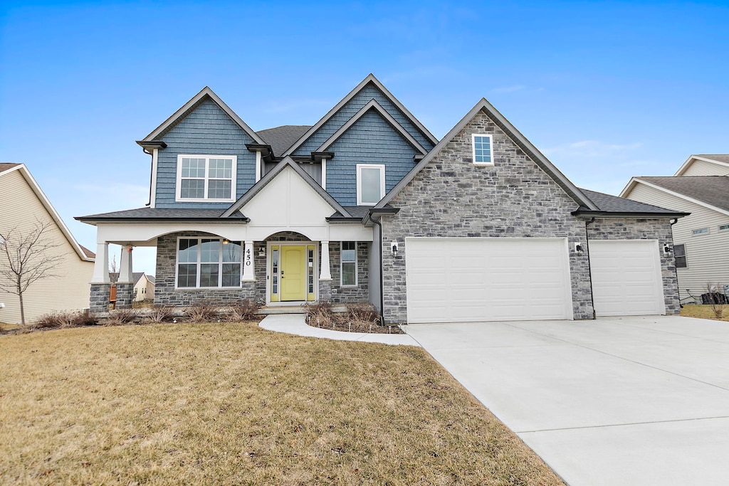 450 Billings Dr, Dekalb, IL 60115 - craftsman house with stone siding, an attached garage, concrete driveway, a front lawn, and a shingled roof