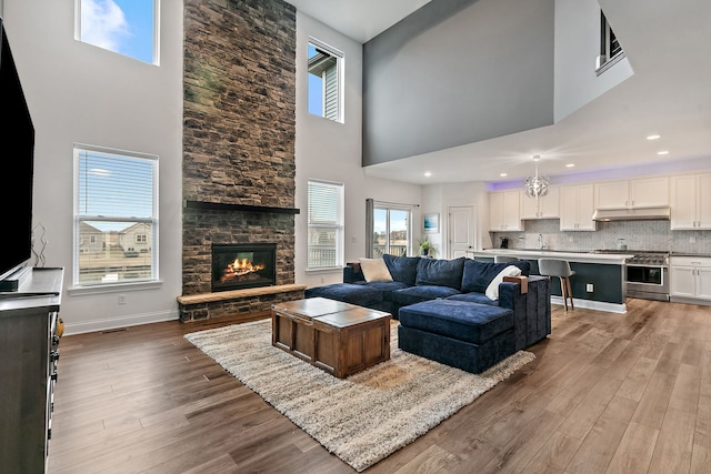 living room featuring recessed lighting, baseboards, a fireplace, and wood finished floors