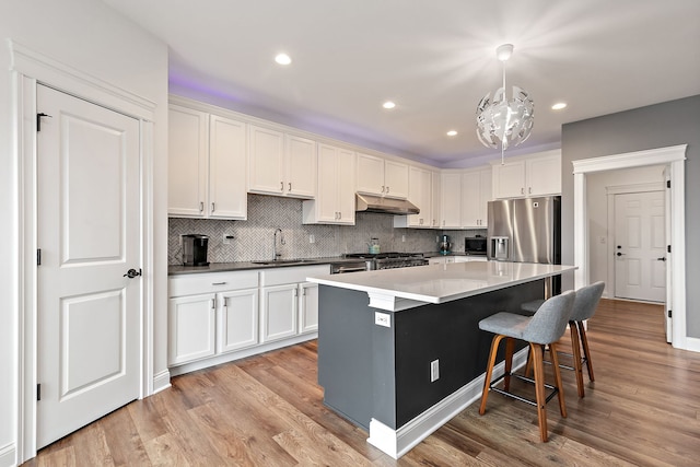 kitchen featuring stainless steel fridge with ice dispenser, under cabinet range hood, white cabinets, and light wood finished floors