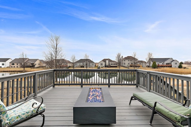 wooden terrace with a water view, an outdoor fire pit, and a residential view
