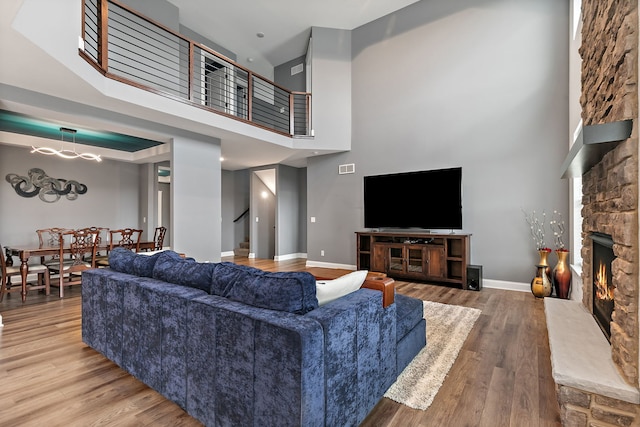 living room featuring a stone fireplace, baseboards, stairs, and wood finished floors
