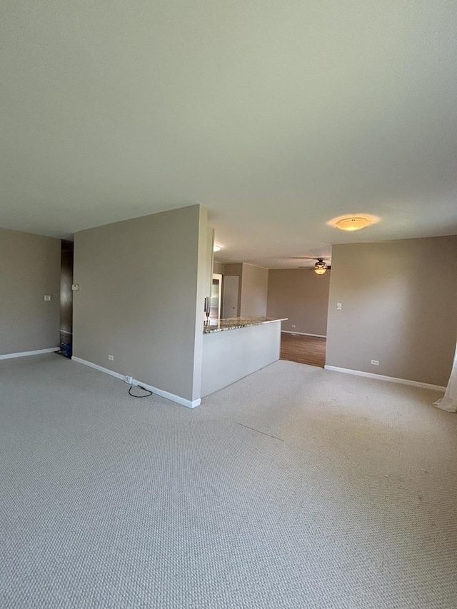 unfurnished living room featuring a ceiling fan, baseboards, and carpet floors