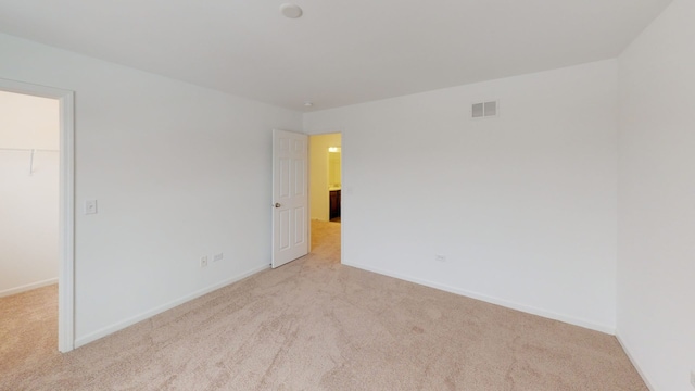 unfurnished room featuring visible vents, baseboards, and light colored carpet