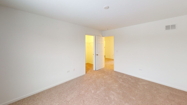 unfurnished room featuring visible vents, light colored carpet, and baseboards