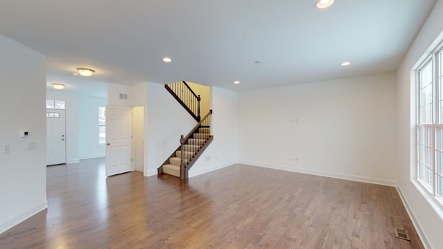 unfurnished living room featuring baseboards, recessed lighting, stairway, visible vents, and wood finished floors