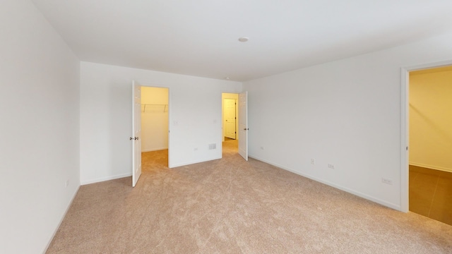 spare room with baseboards and light carpet