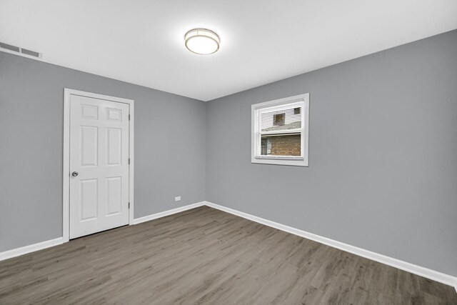 unfurnished room featuring visible vents, baseboards, and wood finished floors