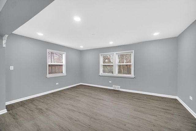 empty room with baseboards, dark wood-style floors, visible vents, and recessed lighting