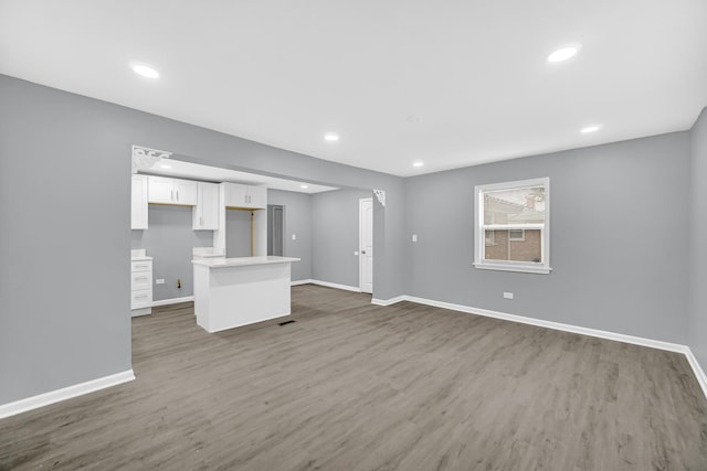 unfurnished living room with baseboards, dark wood-style floors, and recessed lighting