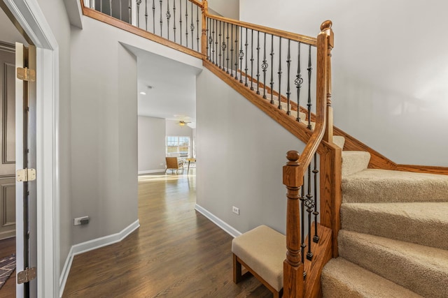 stairs with baseboards, ceiling fan, and wood finished floors