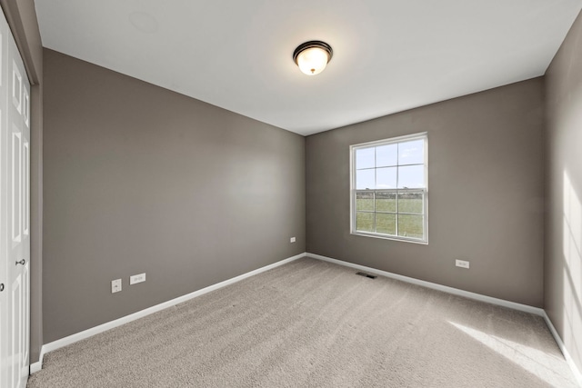 carpeted empty room featuring baseboards and visible vents